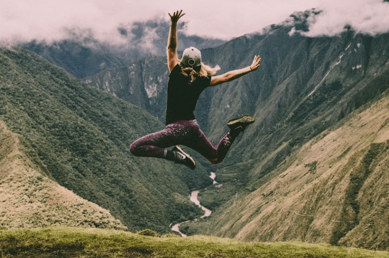 Woman jumping high in natural abundance, expressing the joy of living a fulfilling life