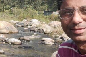 Sukhvinder Sidhu sitting by the side of a stream, enjoying the blissful moments of life
